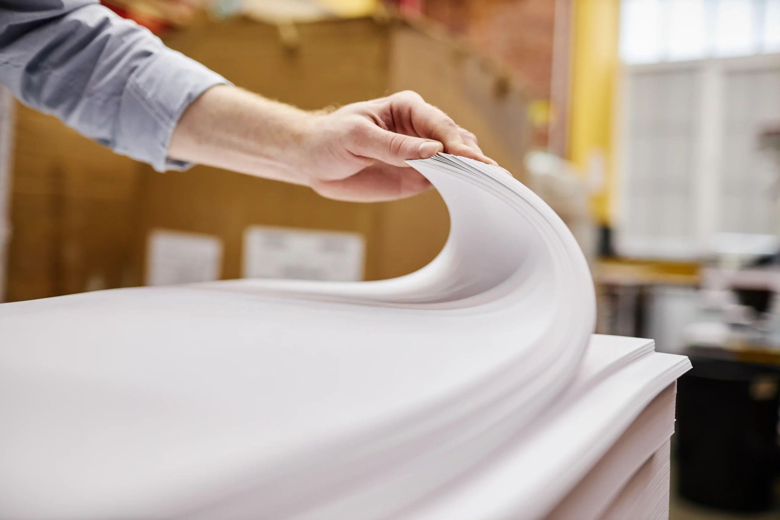 kcopyclose up of person checking quality of paper stack in printing shop, copy space