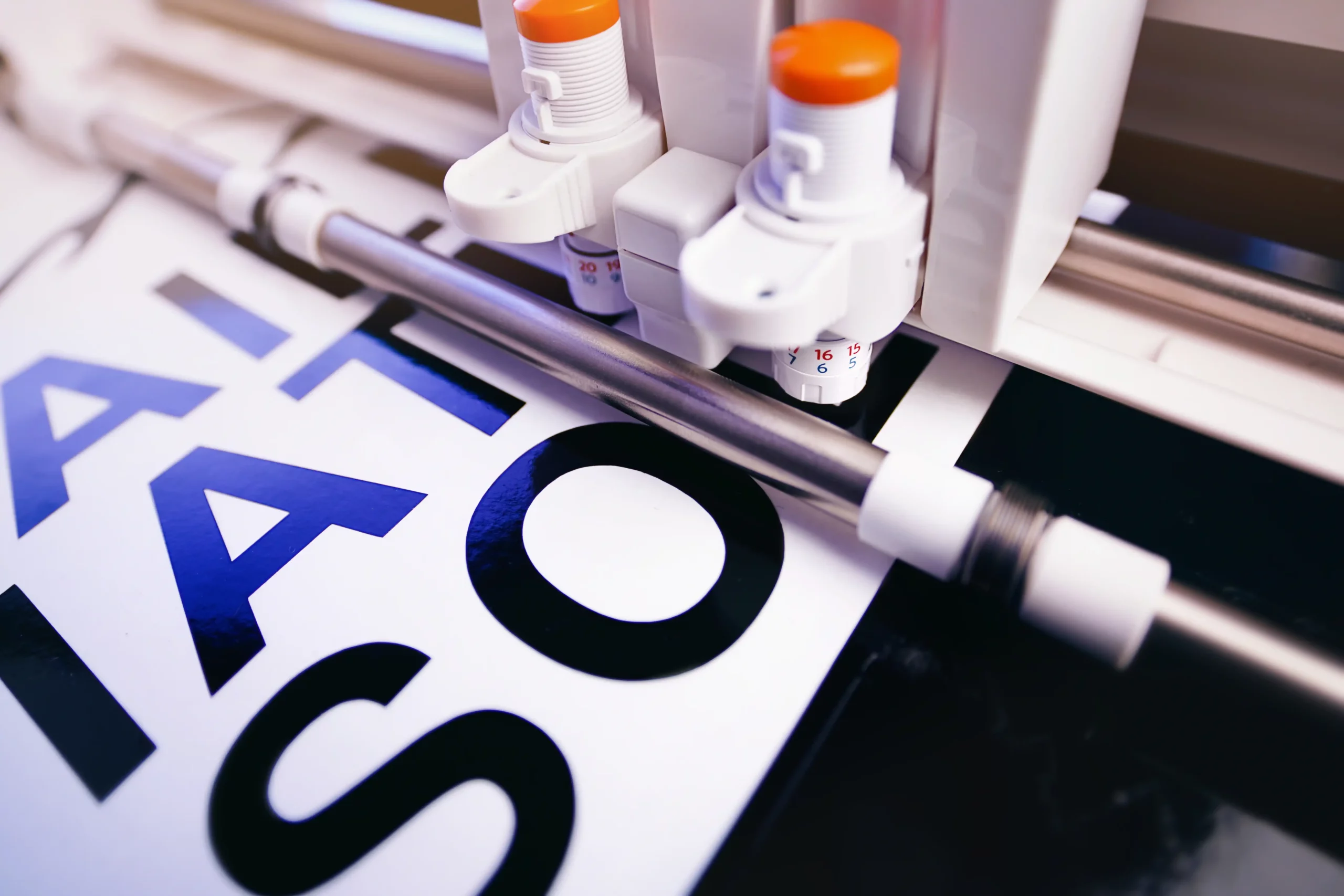 kcopytool head of cutting plotter equiped with two adjustable blades makes adhesive lettering from black vinyl foil in bright light. selective focus. advertising concept
